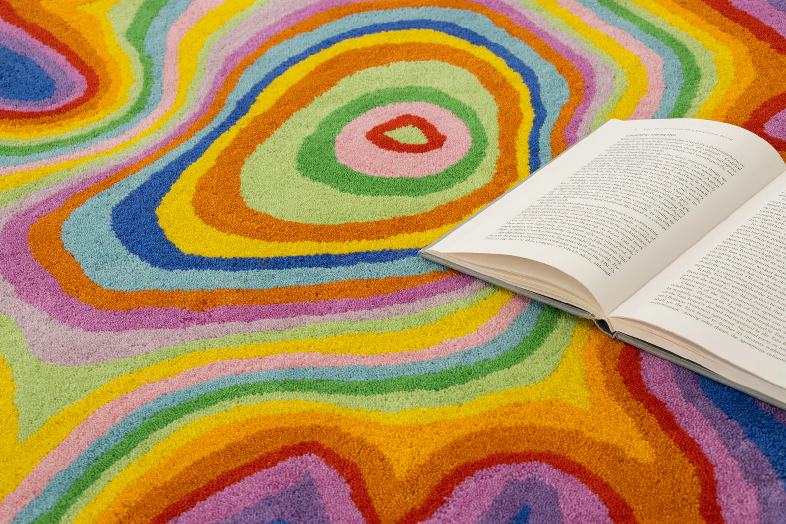 Open book on a colorful abstract-patterned rug.