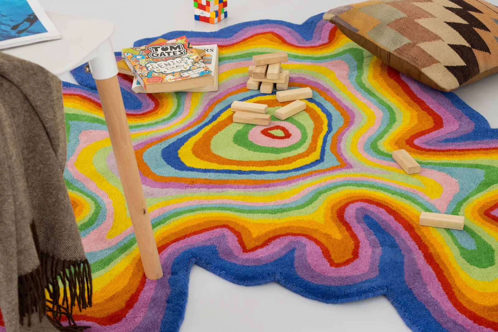 Colorful abstract rug with wooden blocks and book on a white floor.