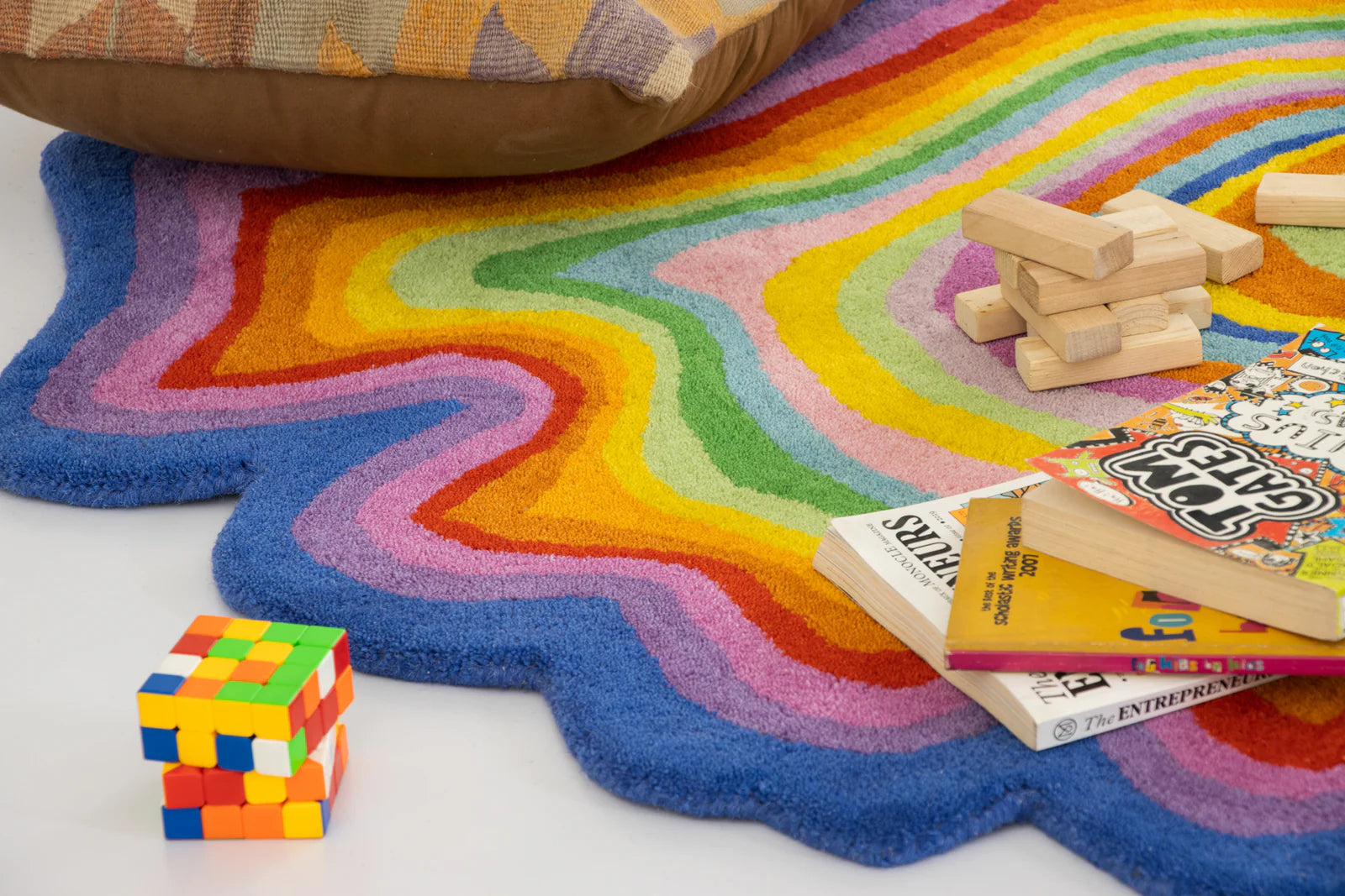 Colorful wavy rug with toys and books on a white background