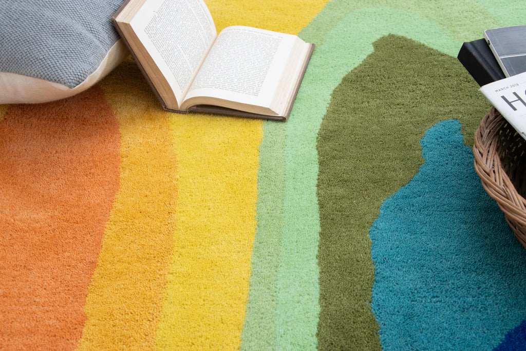 Colorful gradient rug with a book and pillow on a wooden floor.