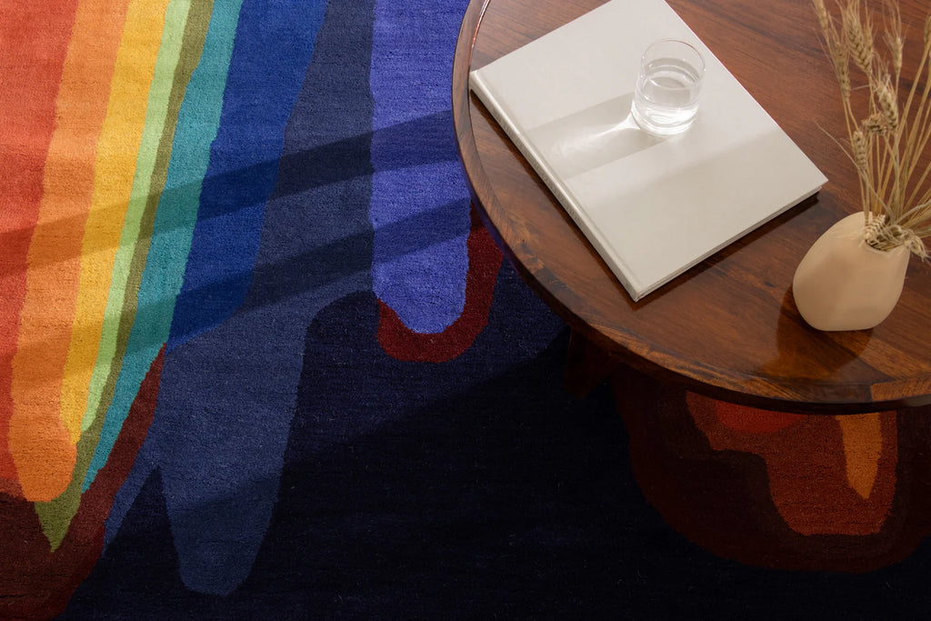 Colorful rug with rainbow pattern next to a wooden table.