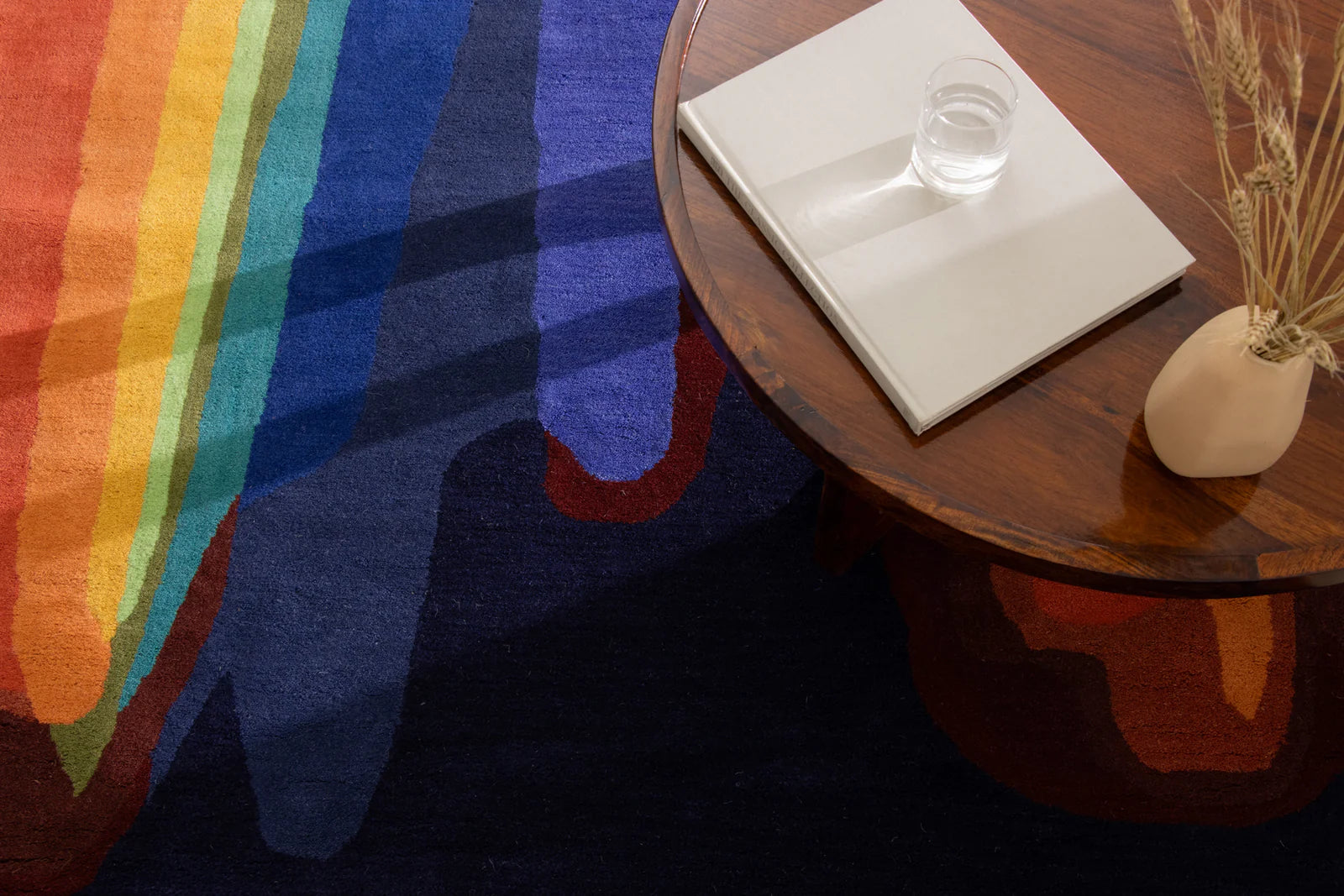 Colorful rug with rainbow pattern next to a wooden table.